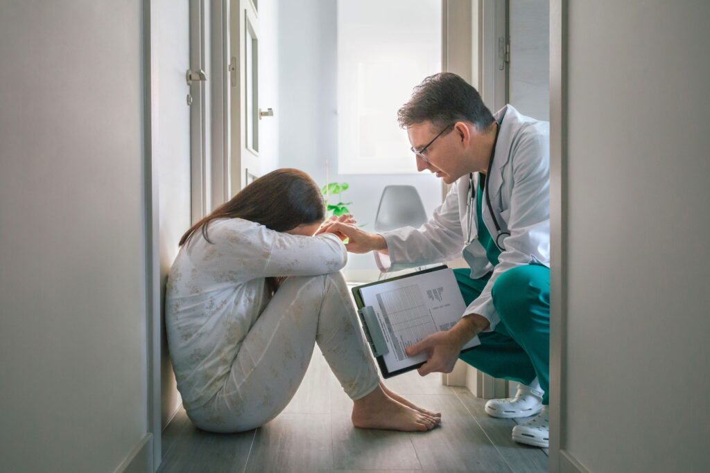 doctor consoling a woman sitting on the floor with her head in her lap struggling with is bipolar and borderline personality disorder the same