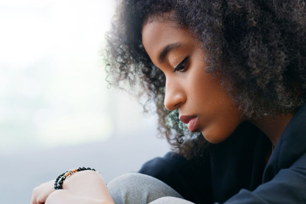 woman sitting down showing the  warning signs for self-harm